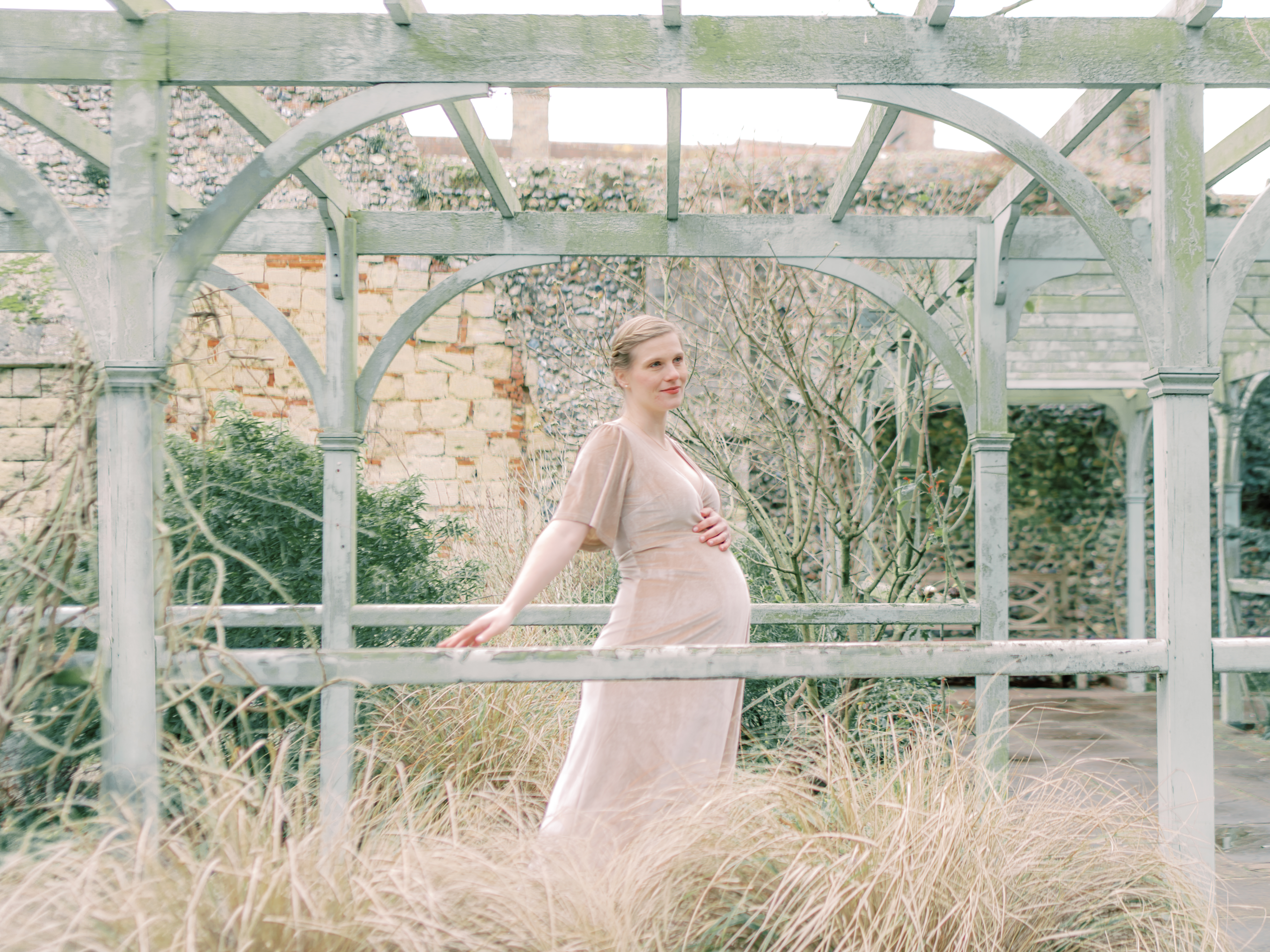 Mother gracefully glides along in enchanting gardens during her professional maternity photo session.