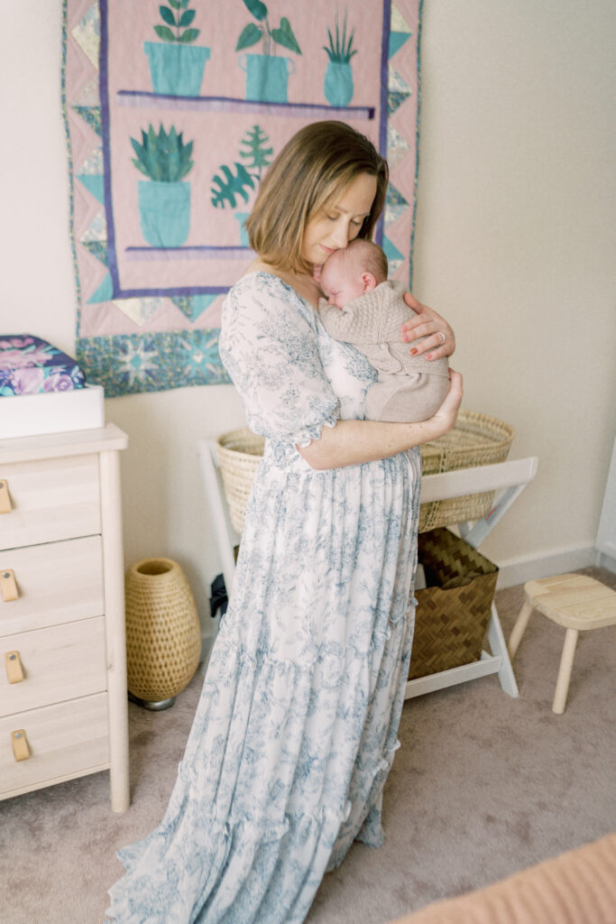 Mother swaying and cuddling her newborn daughter during professional photo shoot by Courtney Cronin Photography in Oklahoma