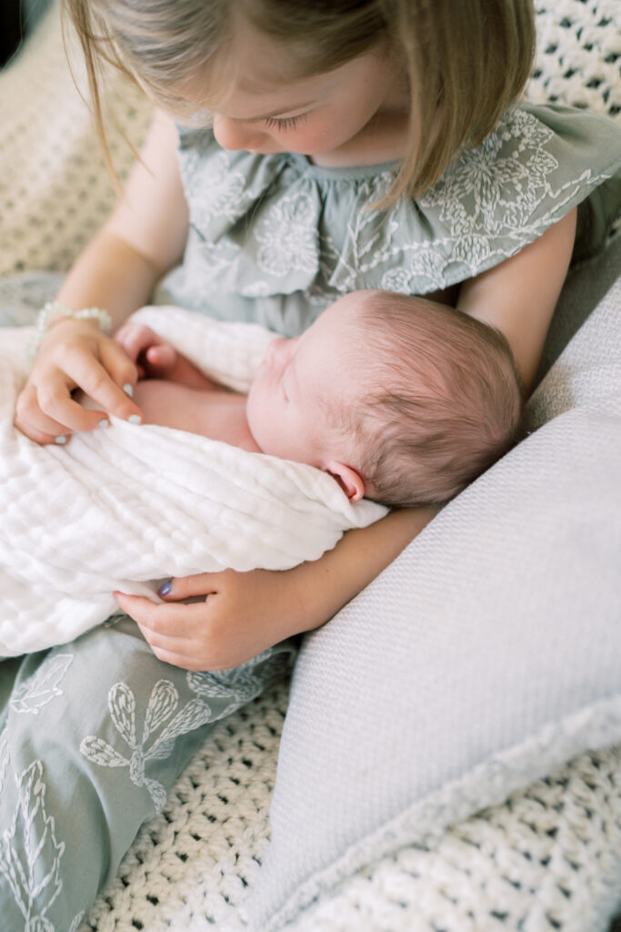 Photo of older sister cradling her newborn baby brother by OKC family Photographer Courtney Cronin