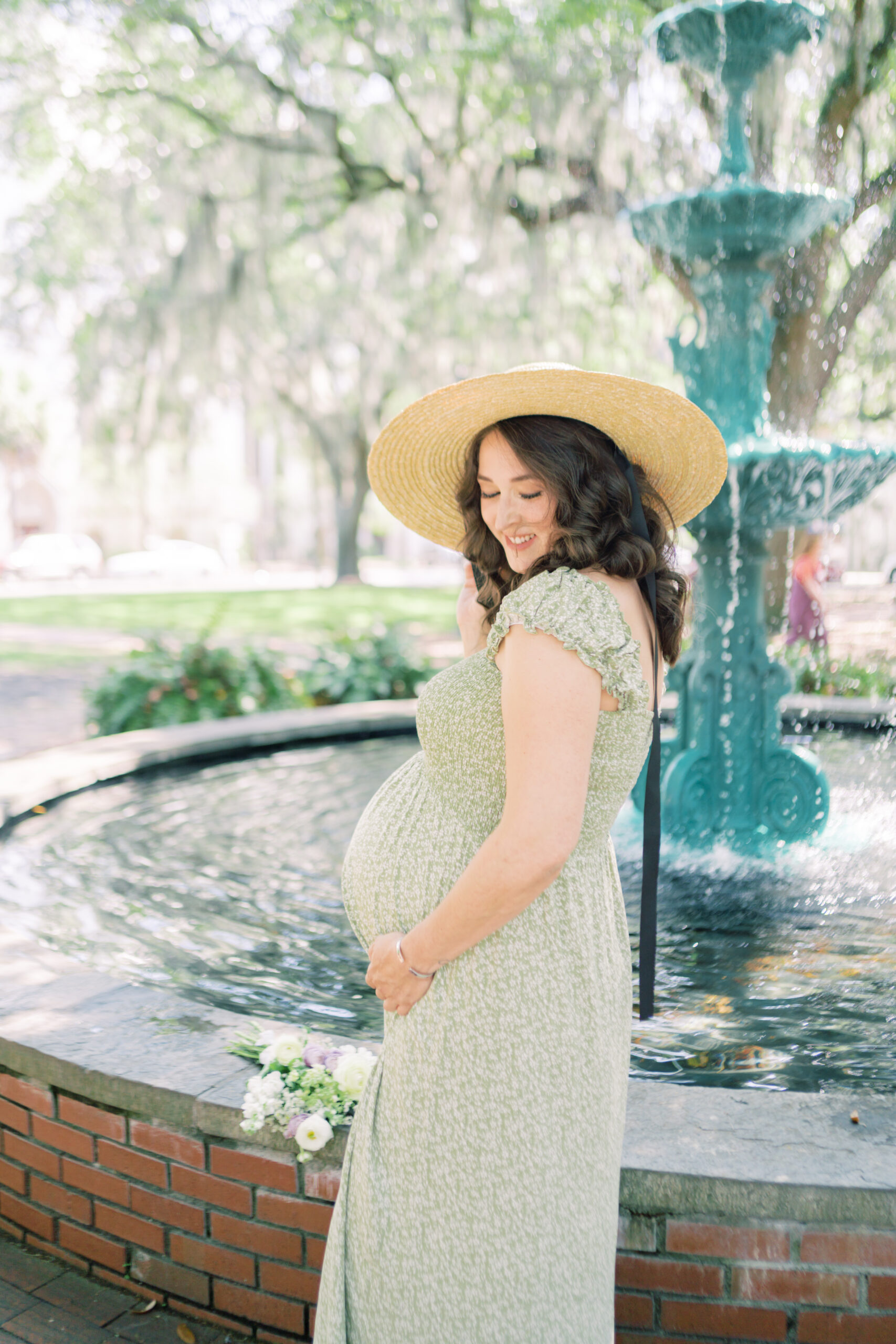 Mother smiles as she touches her baby bump by Savannah Family Photographer Courtney Cronin