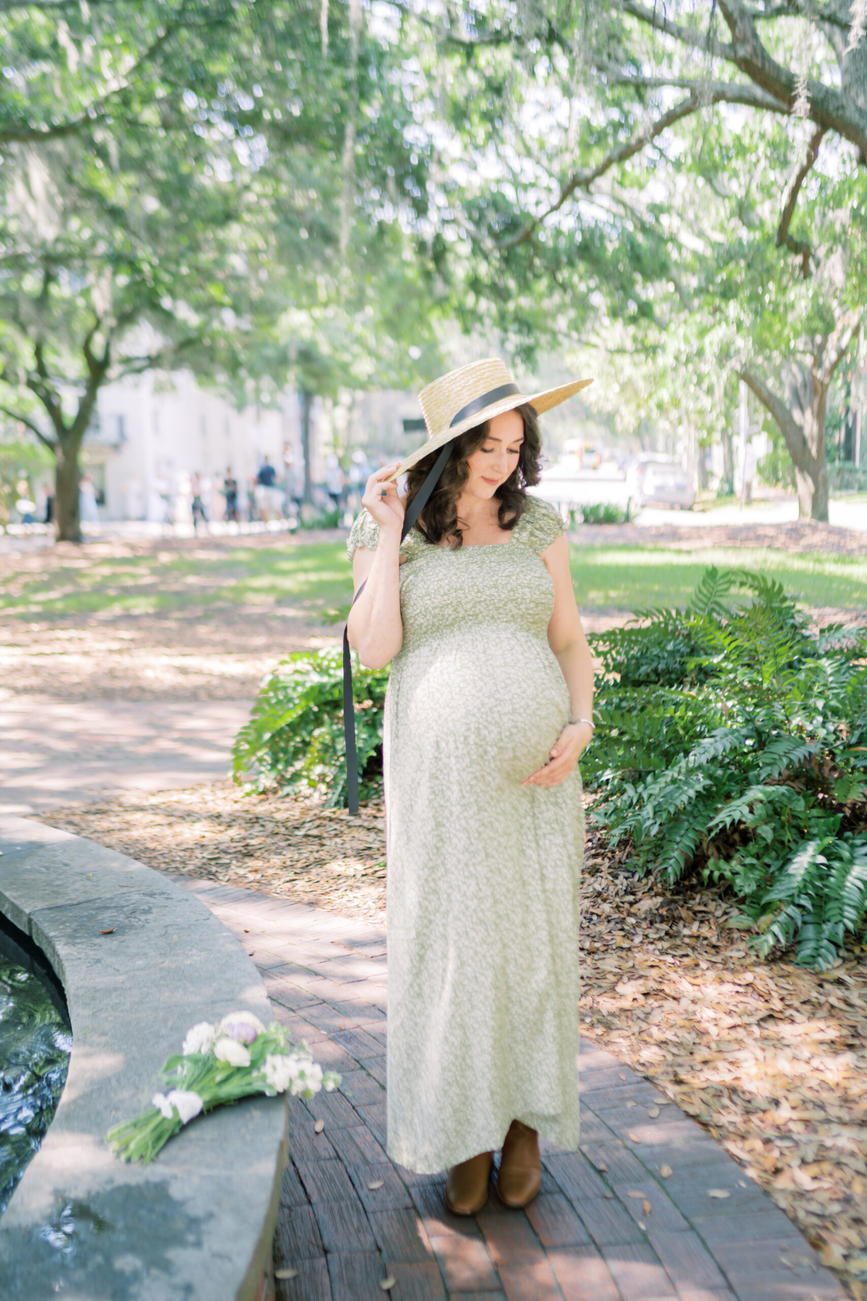 Pregnant mother looks down at her bump while standing in a square by Savannah Family Photographer Courtney Cronin