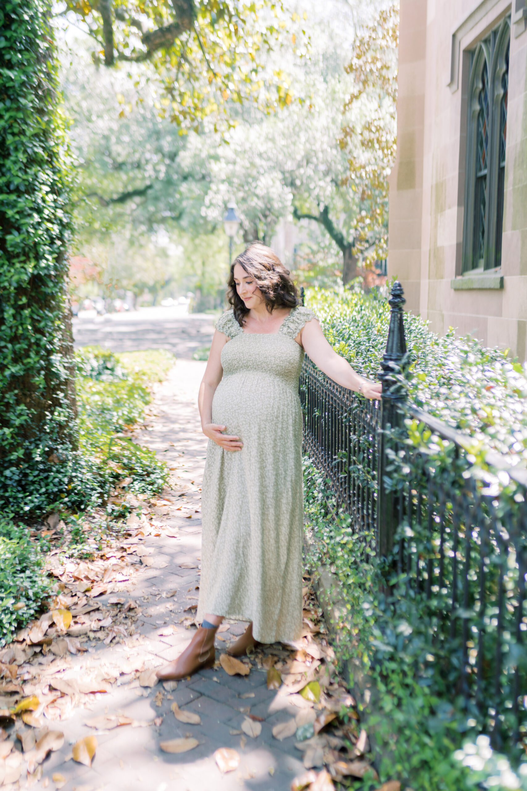 Mother looks down as the sun shines on her hair while she walks through downtown historic district by Savannah Family Photographer Courtney Cronin