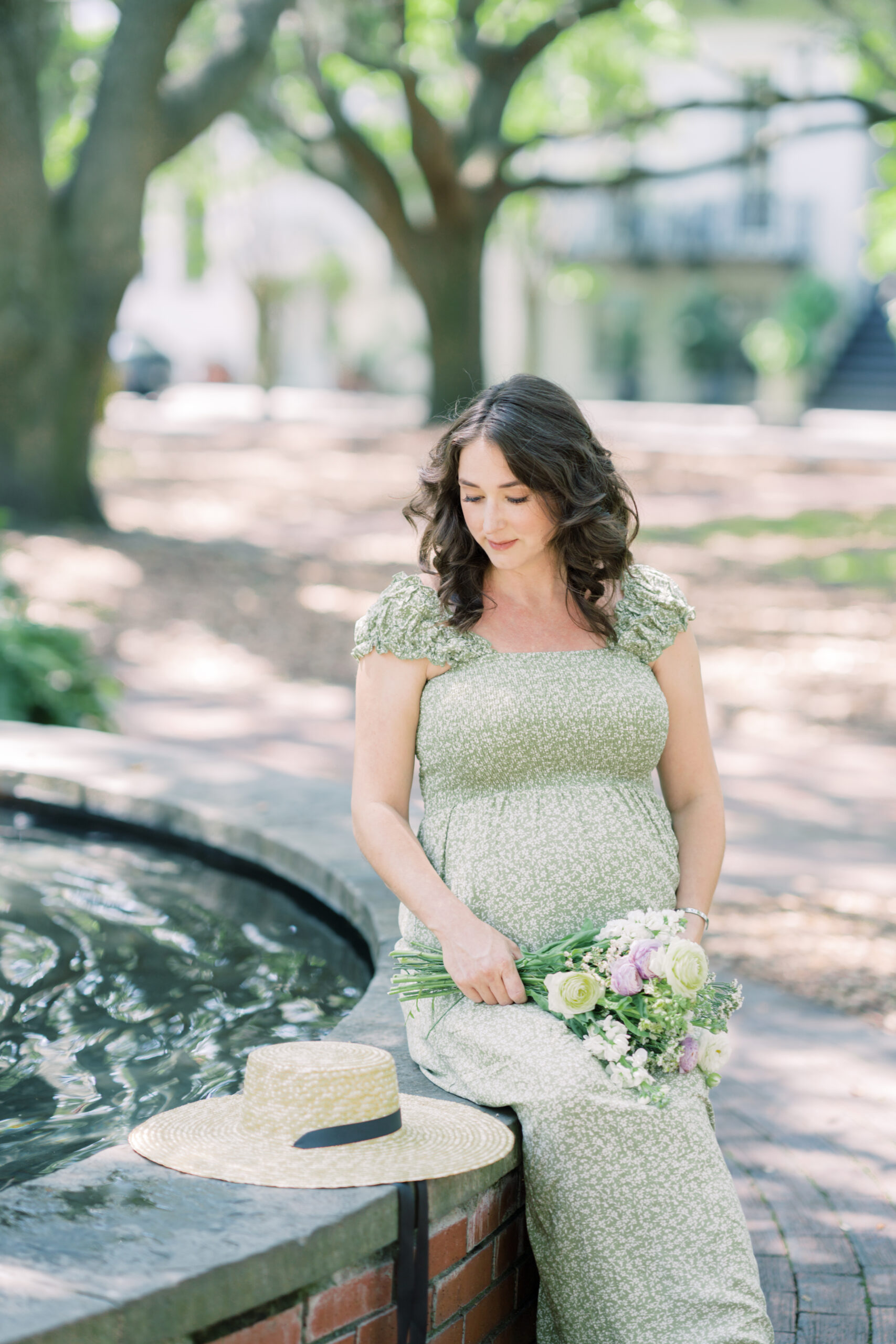pregnant mother sitting on rim of fountain at Lafayette square by Maternity Photographer in Savannah Georgia Courtney Cronin