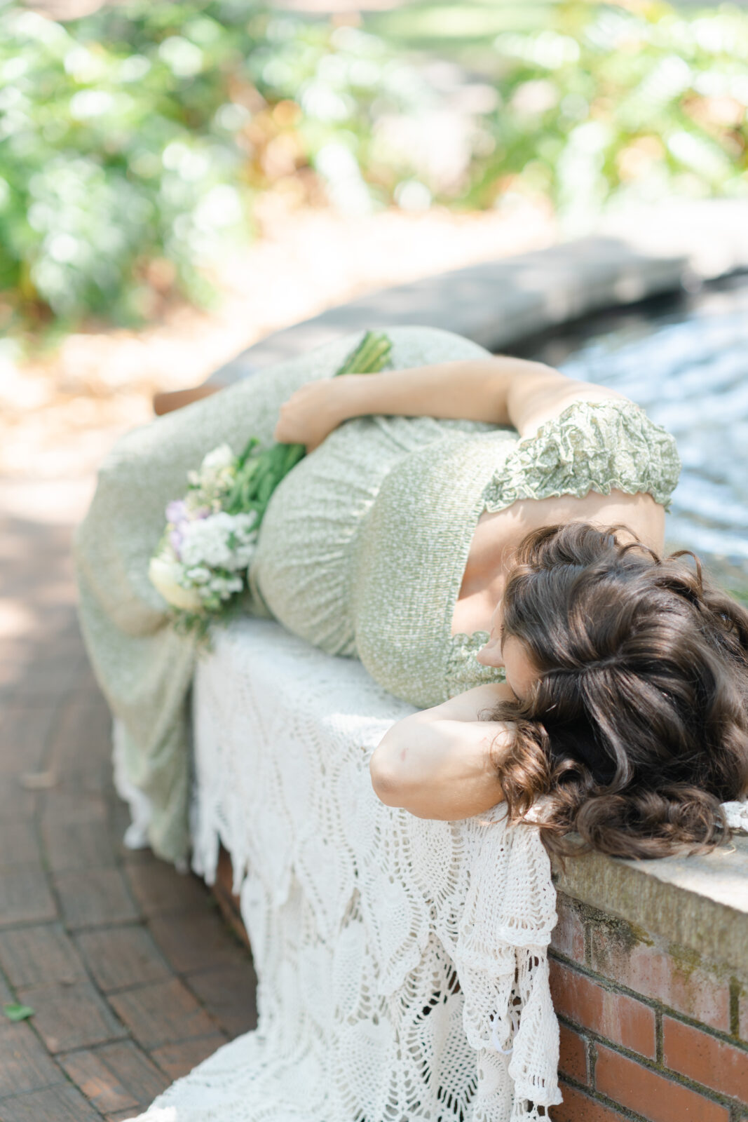 Detail photo of mother holding a bouquet of flowers while laying down on a bench in Lafayette square by Savannah Family Photographer Courtney Cronin